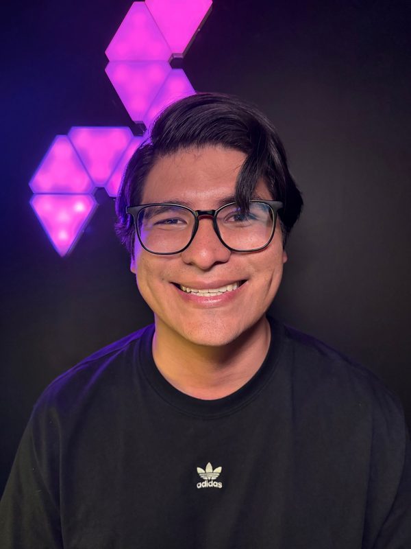 El fundador de Bunedev sonriendo, con lentes y camiseta negra, frente a unos paneles de luz morada